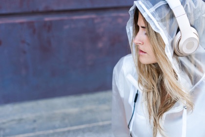 Female wearing a hoodie with  headphones on listening to an audiobook.