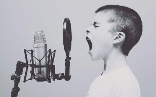 Young boy screaming in to a microphone.