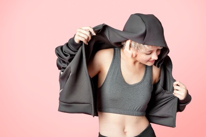 Female with a hoodie jacket on dancing to music.